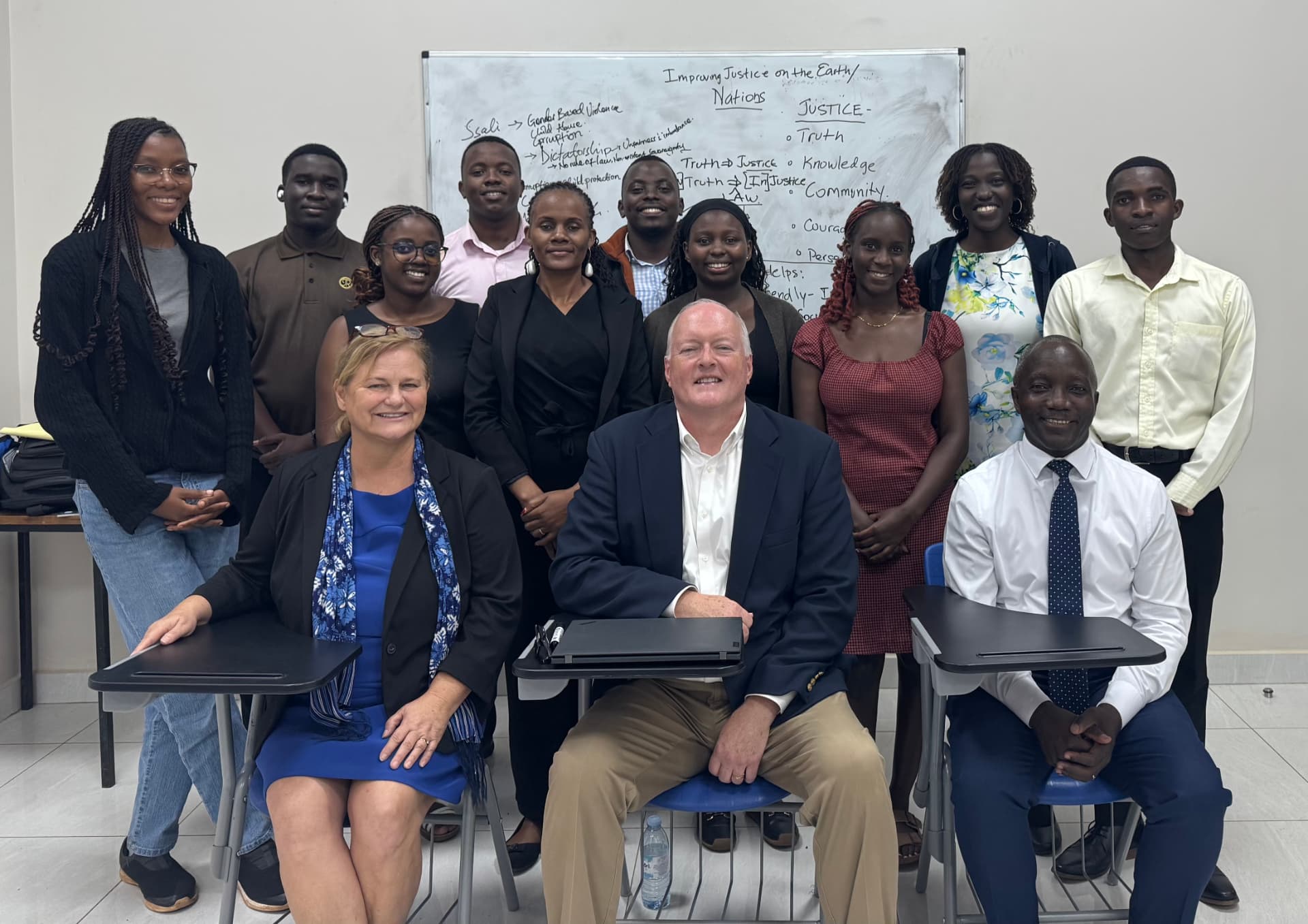 Patrick and Kathleen Talbot seated with a class of African law students in front of a whiteboard exploring the meaning of justice.